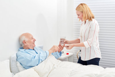 caregiver giving her patient his medication
